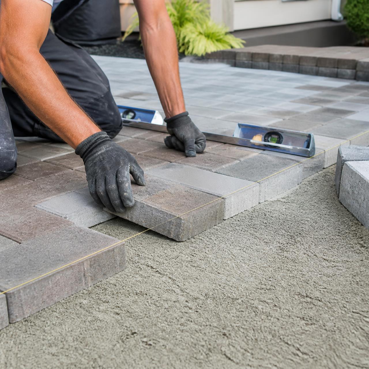 Contractor carefully setting interlocking pavers on a residential patio base